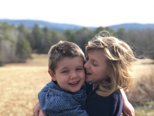 Abigail hugging her brother, Danny, outside in a field
